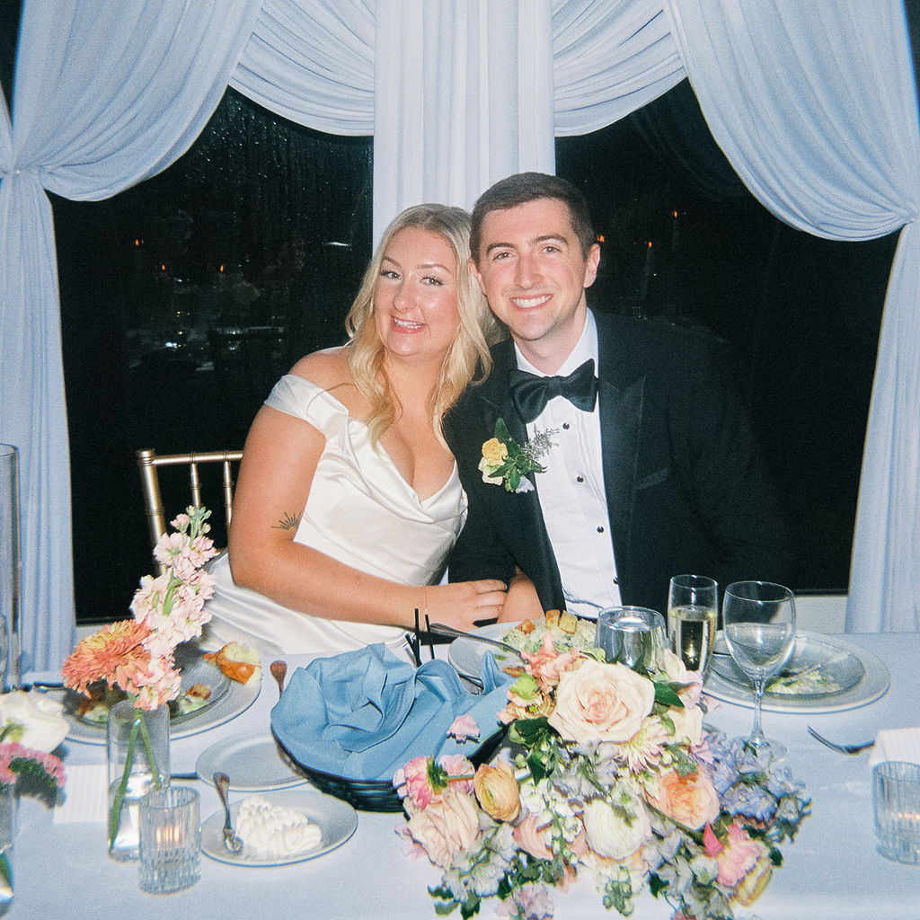 Elegant outdoor reception tablescape with candles and classic florals on film